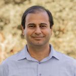 Can Bayram, Ph. D. A middle-aged, Can Bayram, Ph. D., man smiling with a blurred background.