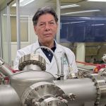 Isaac Hernández Calderón, Ph. D. A middle-aged man, Isaac Hernández Calderón, Ph. D., standing behind molecular beam container.